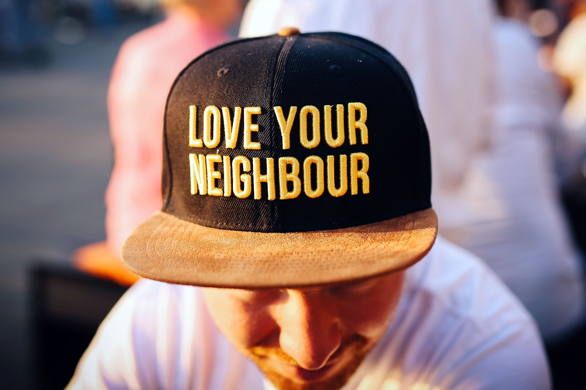 man wearing hat embroidered with 'love your neighbor' text