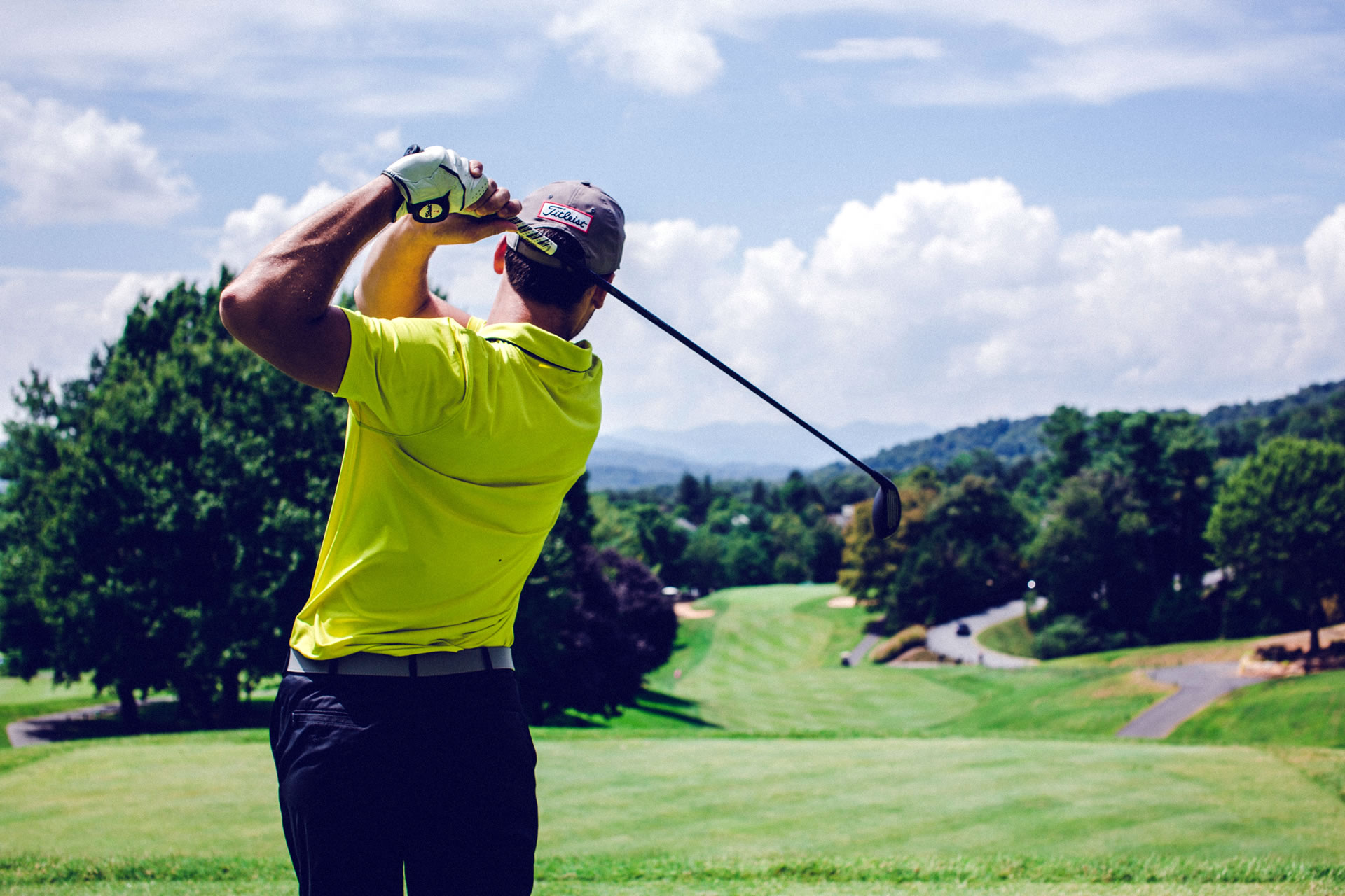 male golfer swinging club and looking down fairway